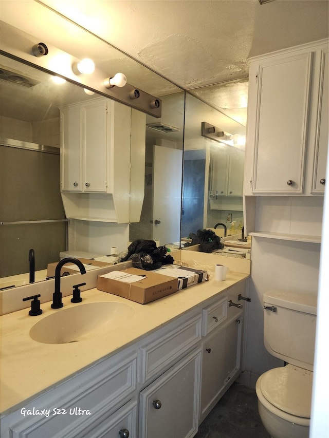 full bathroom featuring a shower with shower door, visible vents, vanity, and toilet