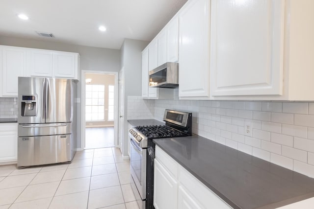 kitchen featuring light tile patterned floors, visible vents, appliances with stainless steel finishes, backsplash, and dark countertops