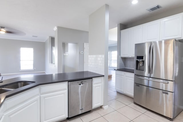 kitchen with a sink, visible vents, appliances with stainless steel finishes, tasteful backsplash, and dark countertops