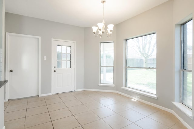 interior space with a chandelier, a healthy amount of sunlight, baseboards, and light tile patterned floors