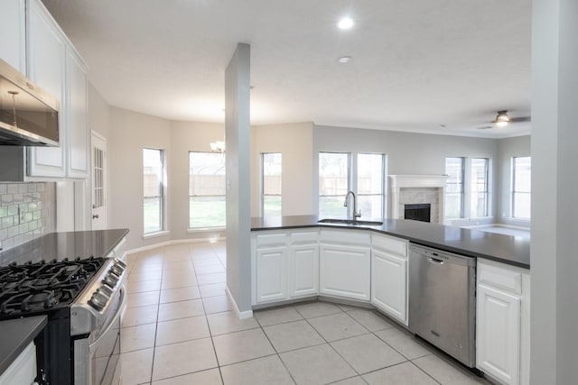 kitchen with appliances with stainless steel finishes, dark countertops, open floor plan, and a sink