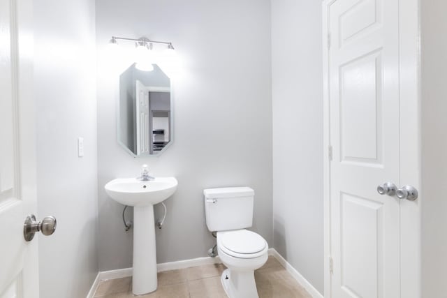 bathroom featuring toilet, tile patterned flooring, and baseboards