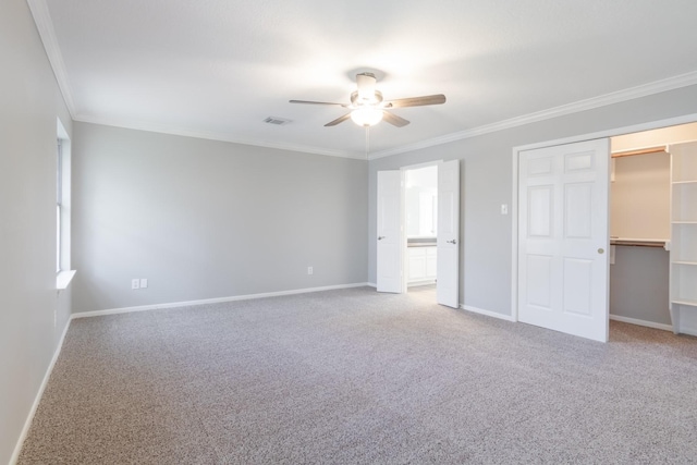 unfurnished bedroom featuring baseboards, visible vents, carpet, a spacious closet, and crown molding