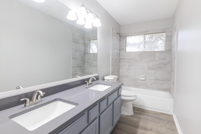 bathroom featuring double vanity, wood finished floors, a sink, and toilet