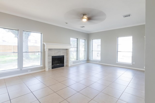 unfurnished living room with ceiling fan, light tile patterned floors, a tile fireplace, visible vents, and ornamental molding