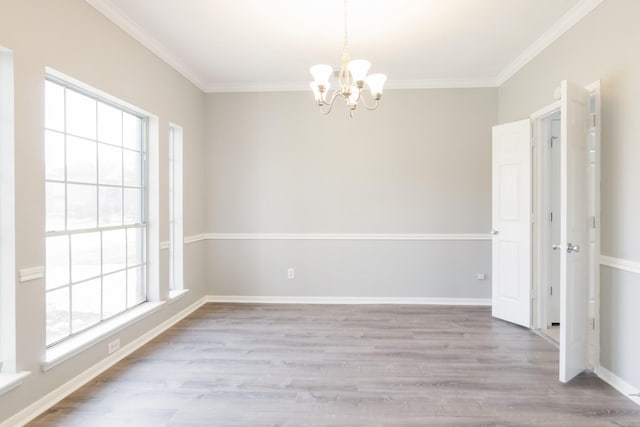 empty room with ornamental molding, a notable chandelier, baseboards, and wood finished floors