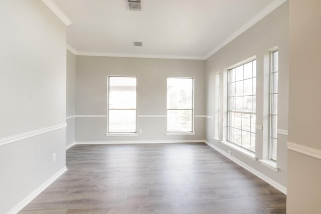 unfurnished room with dark wood-style floors, visible vents, crown molding, and baseboards