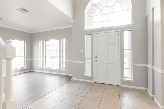 foyer featuring visible vents, crown molding, baseboards, and tile patterned floors