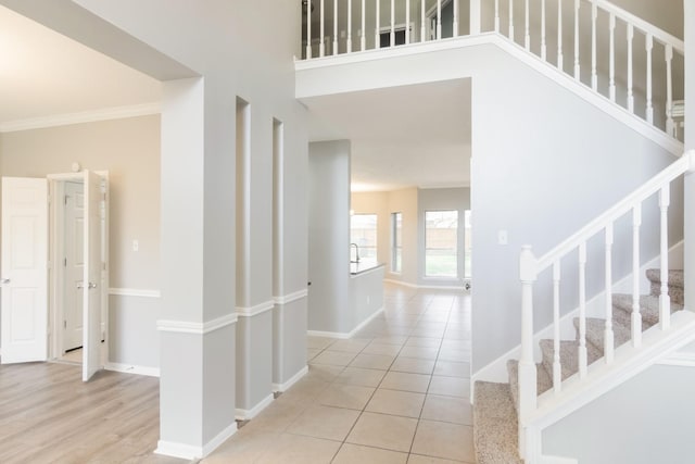 tiled foyer with ornamental molding, stairway, and baseboards