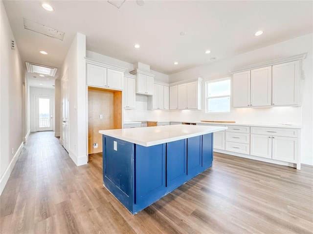 kitchen featuring recessed lighting, white cabinetry, a kitchen island, blue cabinets, and light wood-type flooring