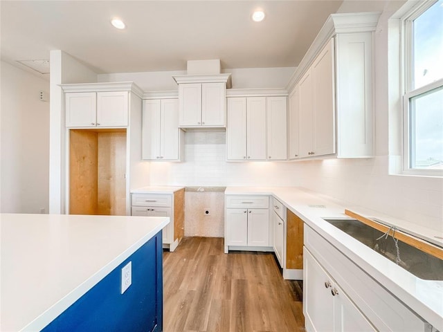 kitchen featuring recessed lighting, a sink, white cabinetry, light wood-type flooring, and backsplash