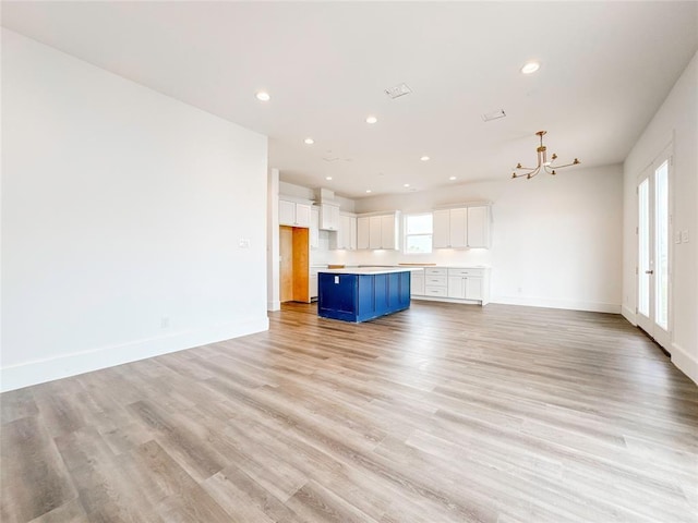 unfurnished living room with recessed lighting, light wood-style flooring, and baseboards