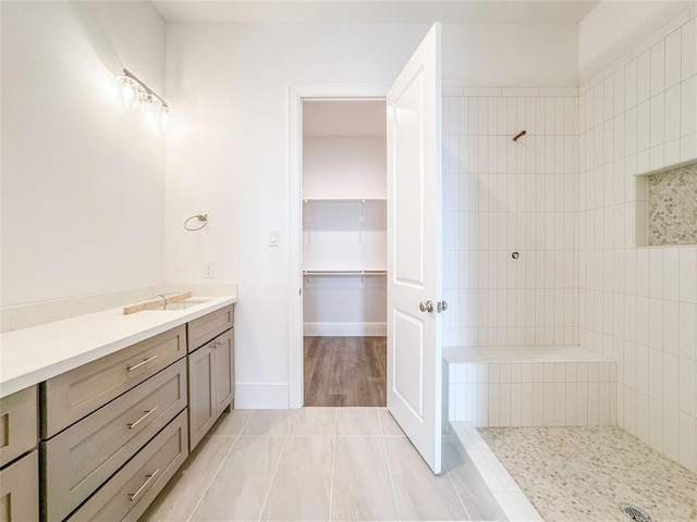 full bathroom featuring vanity, baseboards, a spacious closet, tile patterned floors, and walk in shower