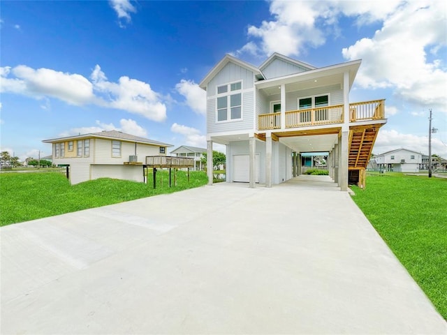 coastal inspired home featuring covered porch, stairs, concrete driveway, a front lawn, and board and batten siding