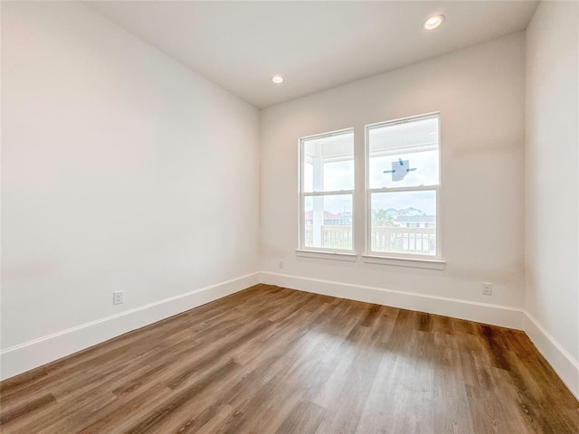 spare room with recessed lighting, baseboards, and wood finished floors