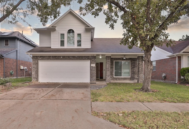 traditional-style house featuring driveway, a shingled roof, an attached garage, a front lawn, and brick siding