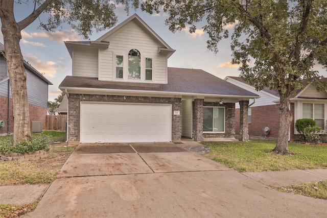 traditional-style house with driveway, a yard, a garage, and brick siding