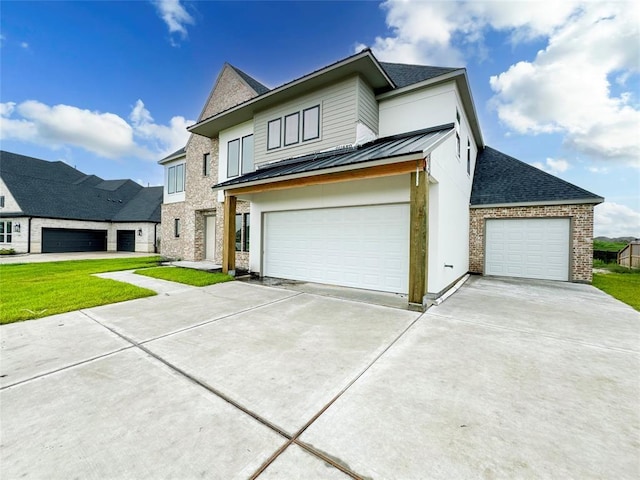 view of front of property featuring a garage, metal roof, a front lawn, and a standing seam roof