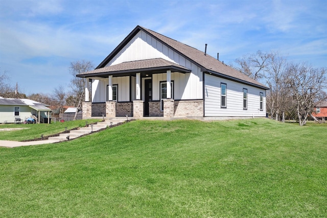 view of front of property with brick siding, roof with shingles, covered porch, board and batten siding, and a front yard