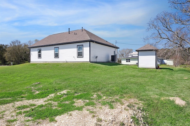 exterior space featuring roof with shingles, a lawn, an outdoor structure, and cooling unit