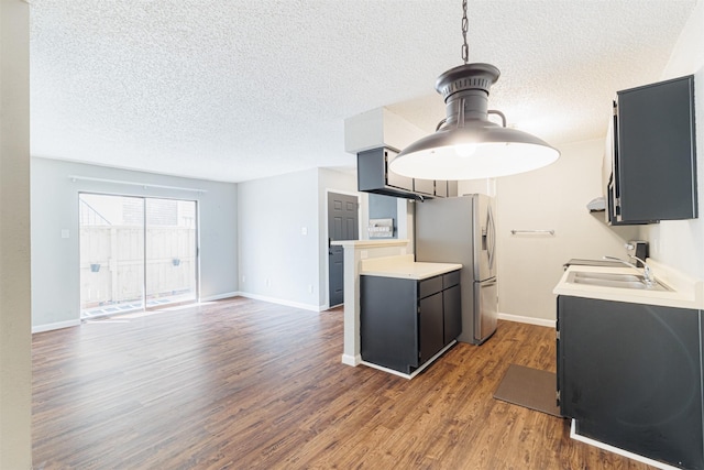 kitchen with a sink, wood finished floors, baseboards, light countertops, and stainless steel refrigerator with ice dispenser