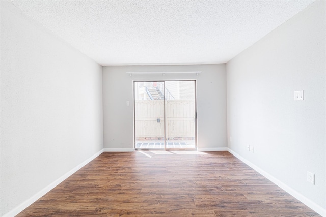 unfurnished room featuring a textured ceiling, baseboards, and wood finished floors