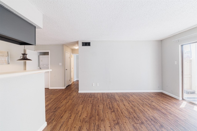 unfurnished living room with baseboards, a textured ceiling, visible vents, and wood finished floors