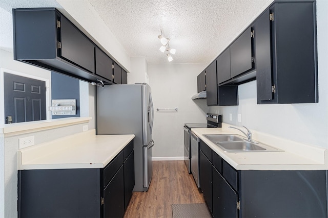 kitchen featuring dark wood-style floors, stainless steel appliances, light countertops, a sink, and a textured ceiling