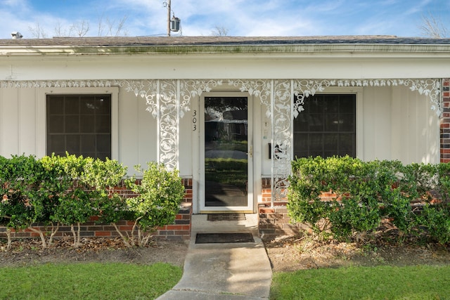 property entrance with brick siding and a shingled roof