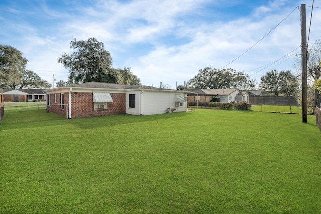 rear view of property featuring brick siding, a lawn, and fence