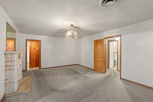 spare room featuring light carpet, a chandelier, and baseboards