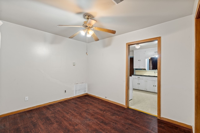 spare room featuring a ceiling fan, visible vents, baseboards, and wood finished floors