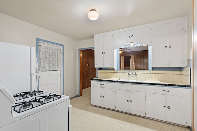 kitchen with tile countertops, white appliances, a sink, white cabinetry, and backsplash