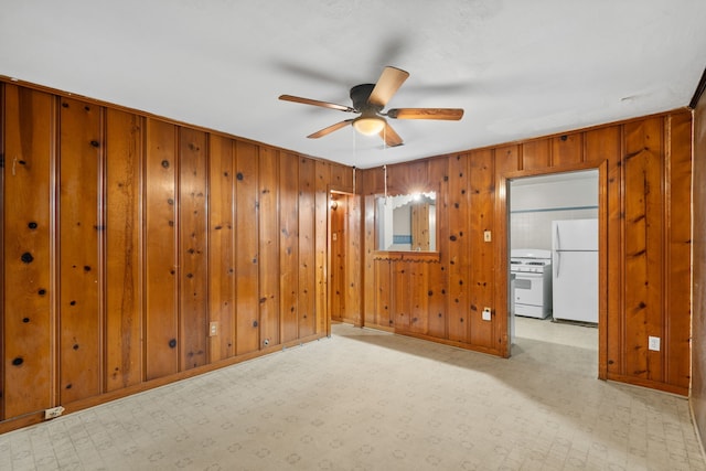 empty room with wood walls, baseboards, a ceiling fan, and tile patterned floors