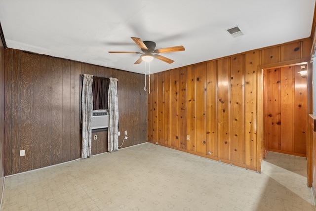 unfurnished room featuring ceiling fan, visible vents, and wooden walls