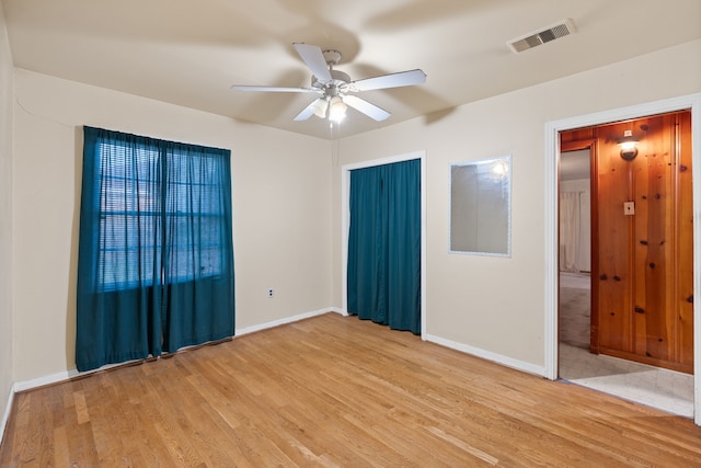 spare room featuring light wood-style flooring, visible vents, ceiling fan, and baseboards