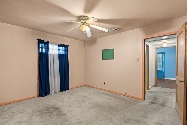 unfurnished room featuring baseboards, visible vents, a ceiling fan, and light colored carpet