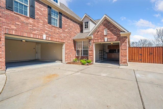 view of front of house with driveway, fence, and brick siding