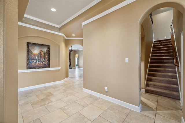 hall with arched walkways, recessed lighting, baseboards, ornamental molding, and a tray ceiling