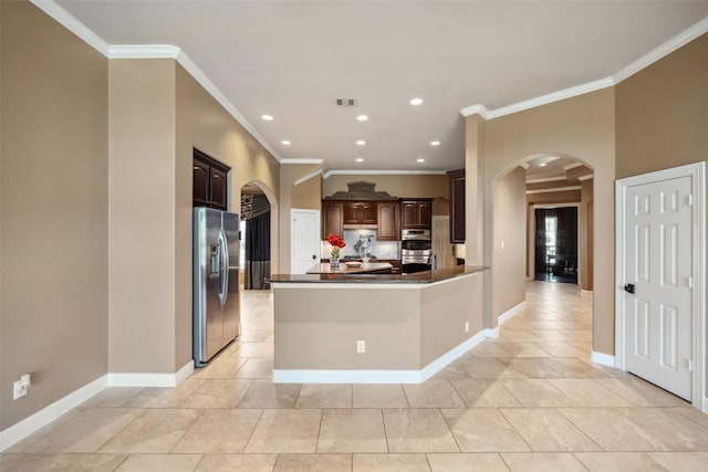 kitchen featuring dark brown cabinetry, arched walkways, dark countertops, a peninsula, and stainless steel appliances