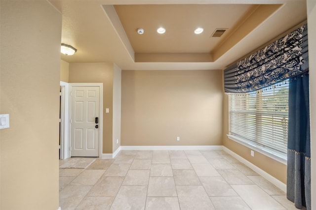 interior space featuring light tile patterned floors, a raised ceiling, visible vents, and baseboards