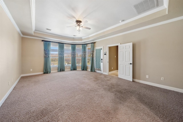 carpeted empty room featuring baseboards, visible vents, a raised ceiling, ceiling fan, and crown molding