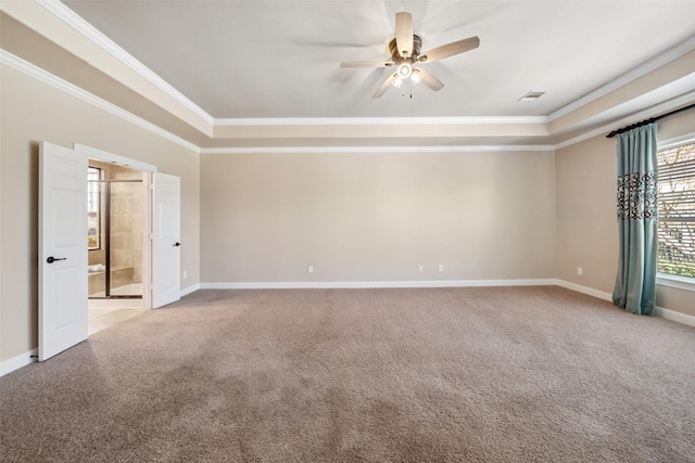 empty room with carpet floors, a tray ceiling, crown molding, and baseboards