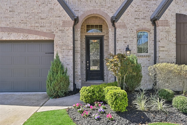 entrance to property with a garage and brick siding