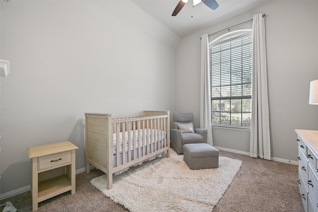 carpeted bedroom featuring a ceiling fan, vaulted ceiling, a crib, and baseboards