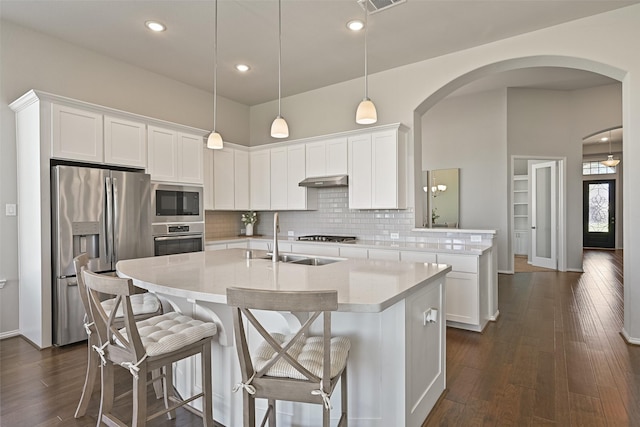 kitchen featuring stainless steel appliances, dark wood-type flooring, a sink, light countertops, and backsplash