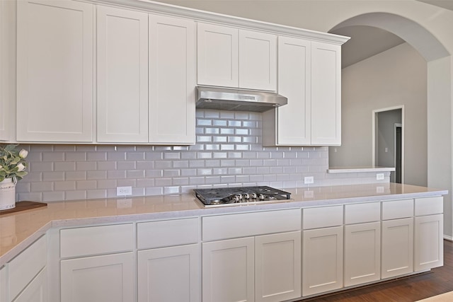 kitchen with under cabinet range hood, stainless steel gas cooktop, white cabinetry, light countertops, and tasteful backsplash