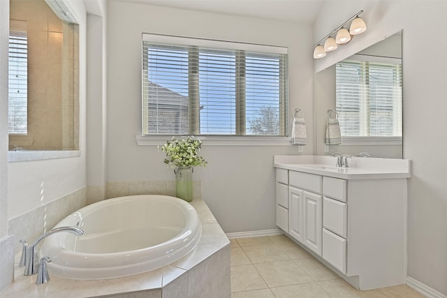 bathroom featuring a garden tub, vanity, baseboards, and tile patterned floors