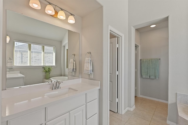 bathroom featuring a tub to relax in, tile patterned flooring, baseboards, and vanity