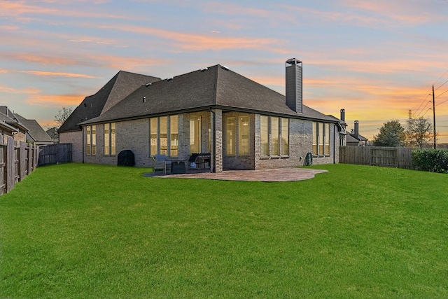 rear view of house featuring a patio area, a fenced backyard, and a lawn